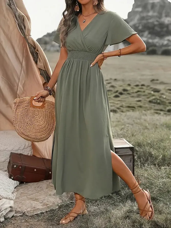 Woman in a green dress holding a straw bag in a natural setting