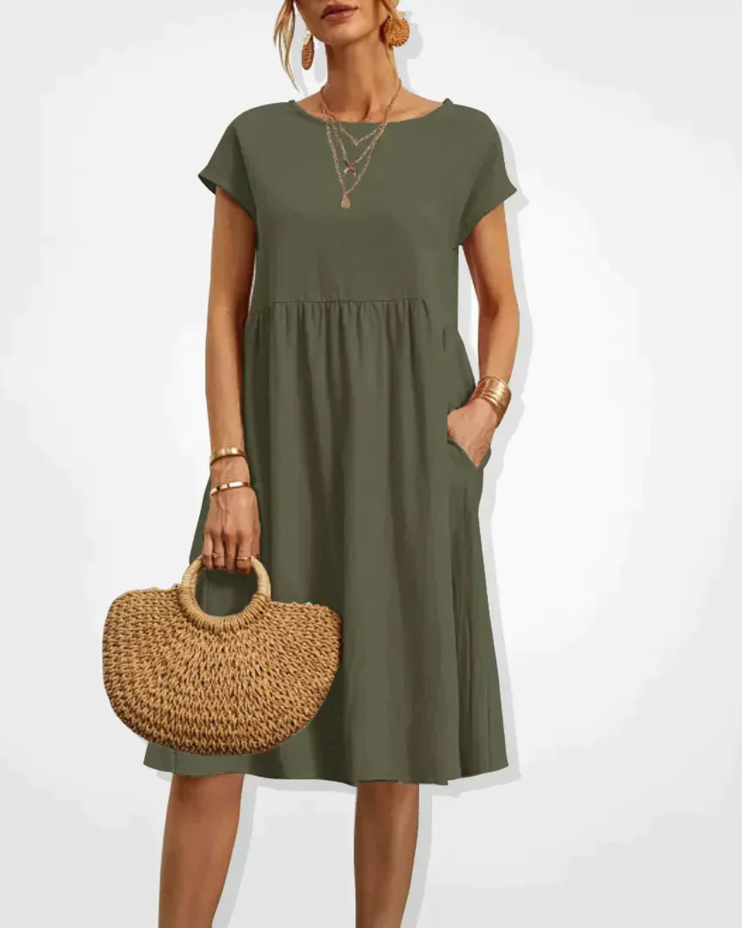Woman wearing an olive green dress holding a woven bag on a white background
