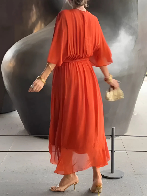 Woman in a red dress standing in front of a large sculpture.