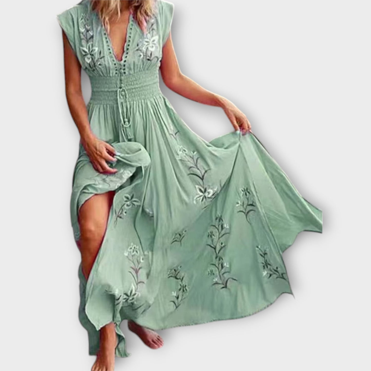 Green embroidered dress being held by a person on a white background