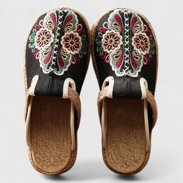 Pair of embroidered sandals with colorful floral patterns on a light gray background