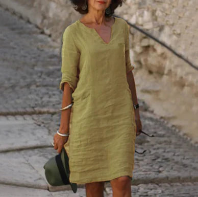 Woman wearing a green dress standing on a stone pavement.