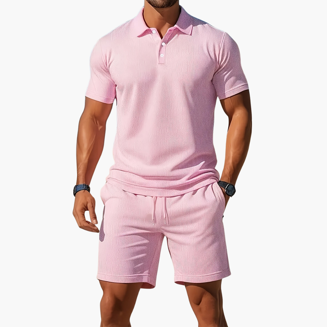 Man wearing a pink polo shirt and shorts set on a white background