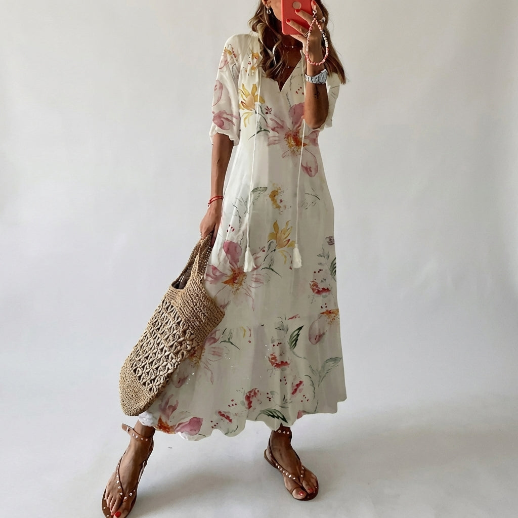 Woman wearing a floral dress holding a woven bag against a plain background