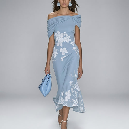 Woman wearing a light blue off-shoulder dress with floral patterns on a gray background
