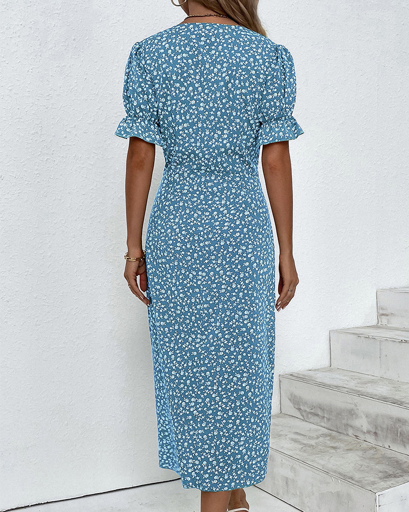 Woman wearing a blue floral dress standing on a white staircase.
