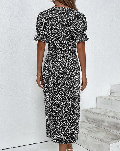 Woman wearing a black floral dress standing on a white staircase.