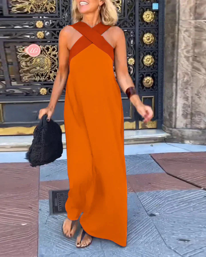 Woman wearing an orange dress with a black bag in front of a decorative door.