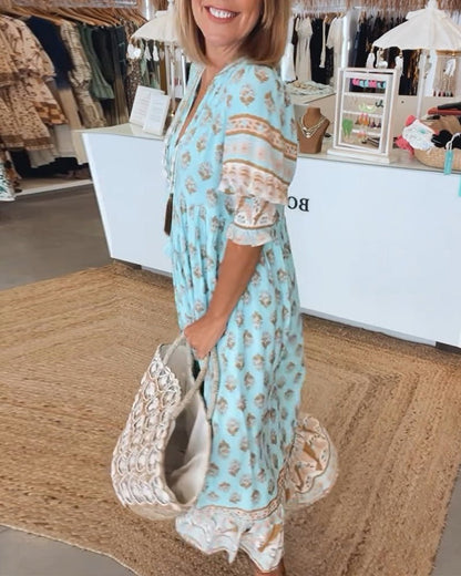 Woman in a light blue dress with a pattern, holding a large white handbag with decorative elements, standing in a store.