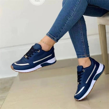 Navy blue sneakers with white accents worn by a person sitting on a chair.