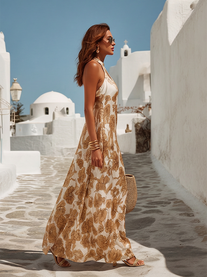 Woman in a floral dress walking on a sunlit street with white buildings.