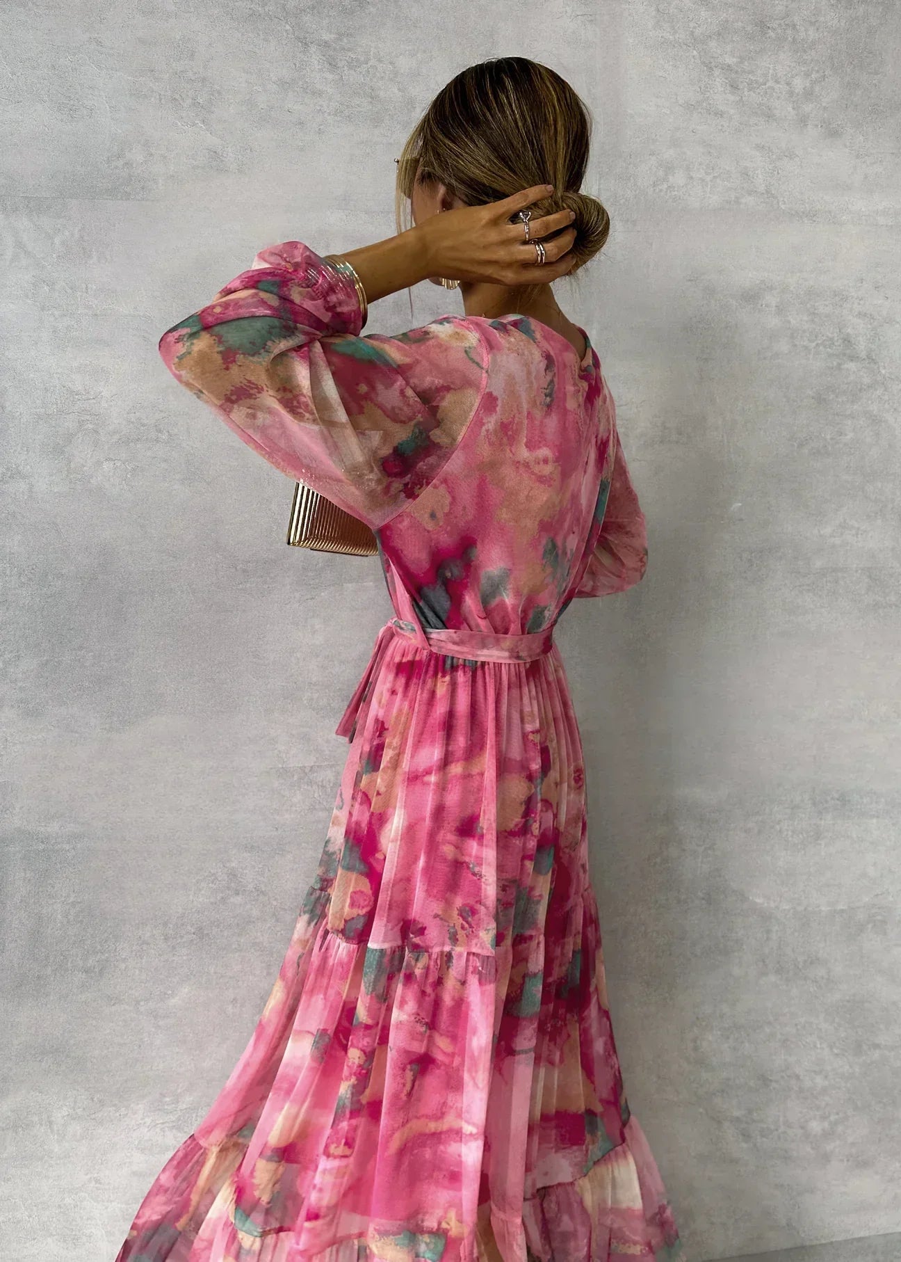 Woman wearing a pink floral dress against a gray background