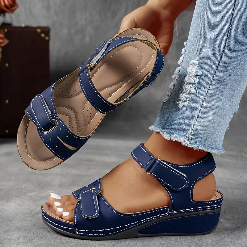 Blue sandals worn with light blue jeans on a gray surface