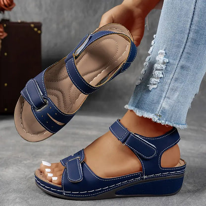 Blue sandals worn with light blue jeans on a gray surface