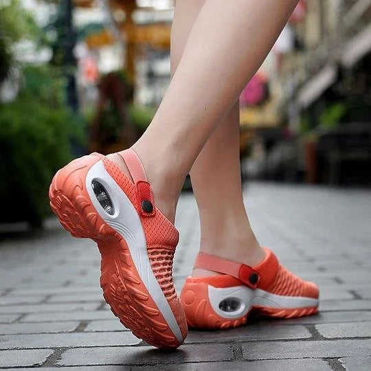 Orange clogs with white soles worn on a blurred outdoor background