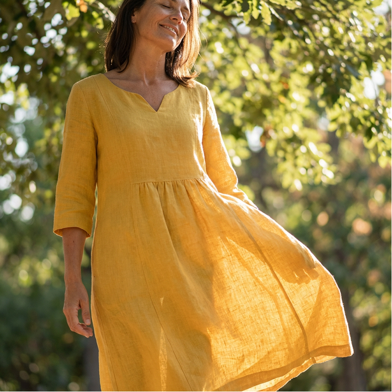Woman wearing a yellow dress standing among trees