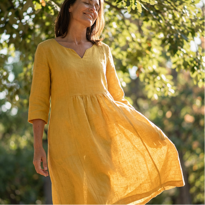 Woman wearing a yellow dress standing among trees