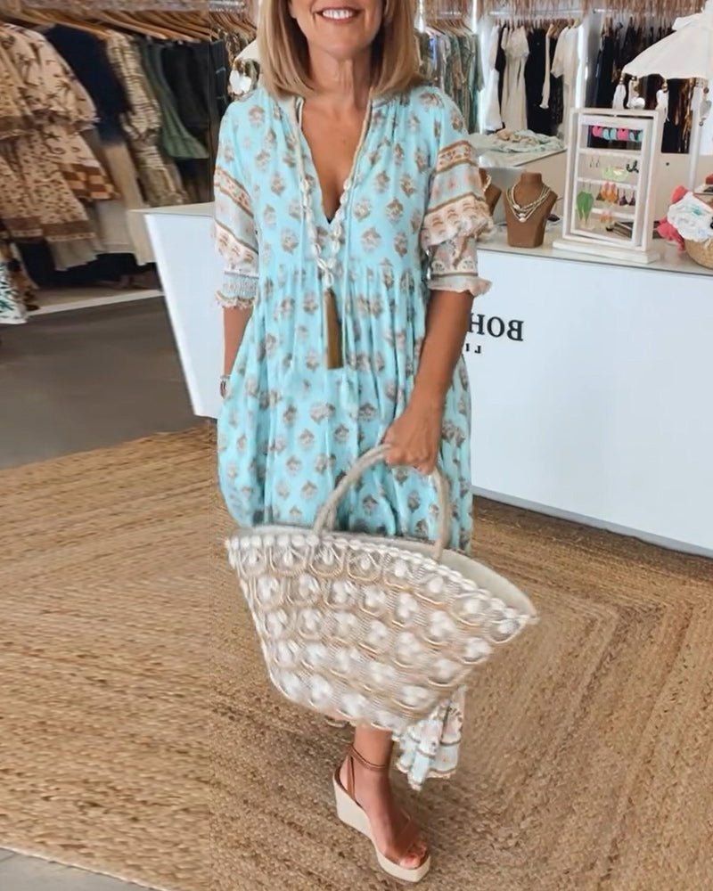 Woman in a light blue dress with floral pattern holding a matching handbag in a store.