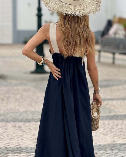 Woman in a black dress and straw hat walking on a street.