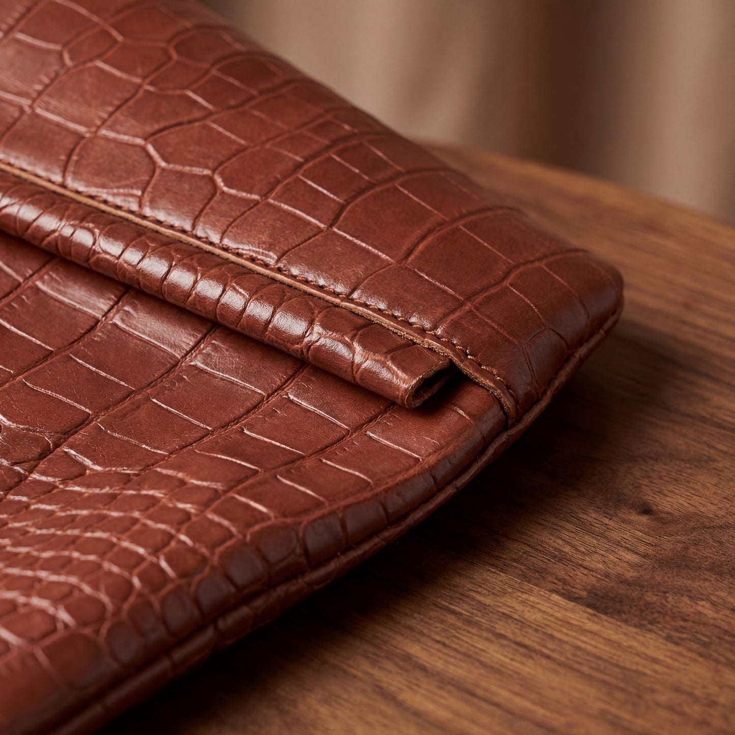 Brown patterned leather tote bag on a wooden surface