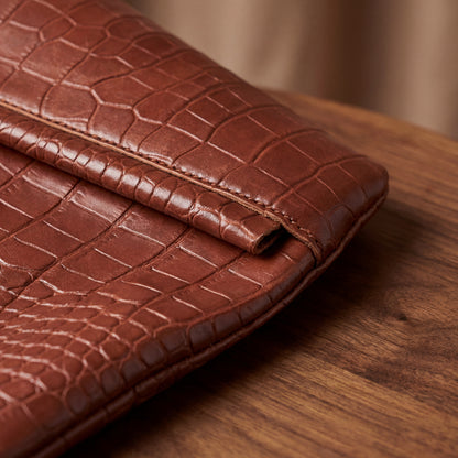 Brown patterned leather tote bag on a wooden surface