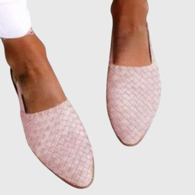 Pink woven flats worn with white pants on a light gray background