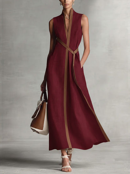 Woman wearing a burgundy dress with a brown strap against a gray background