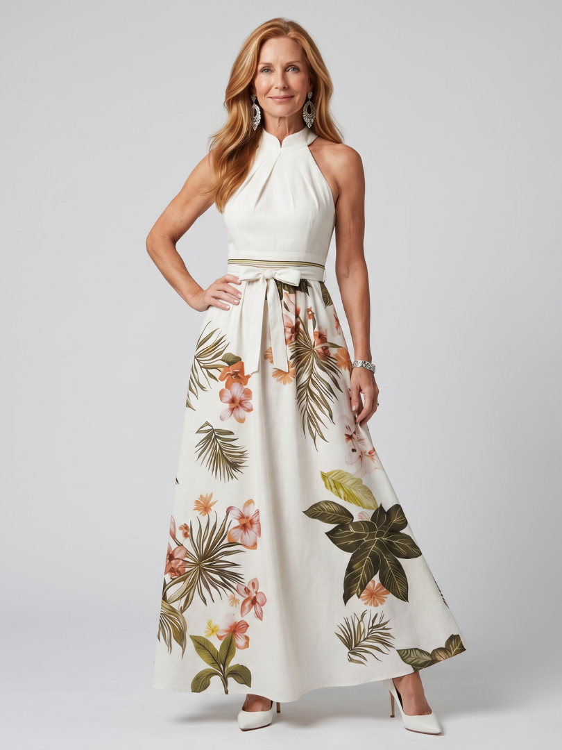 Woman wearing a white halter neck dress with floral and leaf patterned skirt on a plain background
