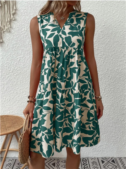Woman wearing a green leaf-patterned dress against a white wall.