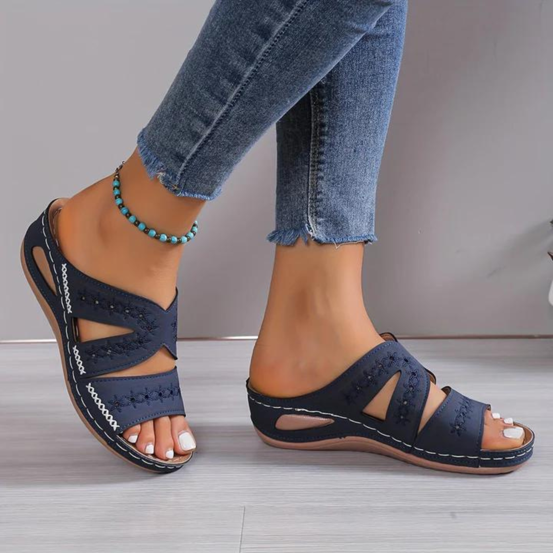 Navy sandals worn with blue jeans on a neutral background