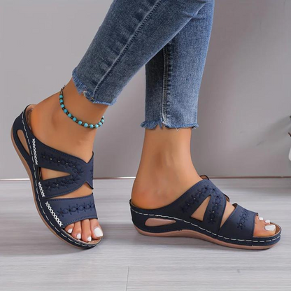 Navy sandals worn with blue jeans on a neutral background