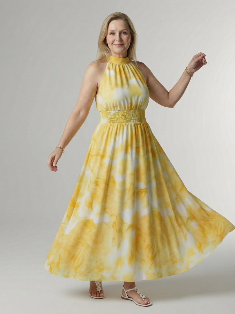Woman wearing a yellow and white tie-dye dress against a plain background