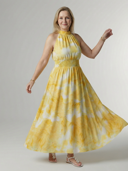 Woman wearing a yellow and white tie-dye dress against a plain background