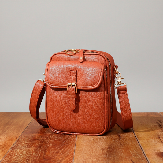 Brown leather crossbody bag on a wooden surface with a neutral background