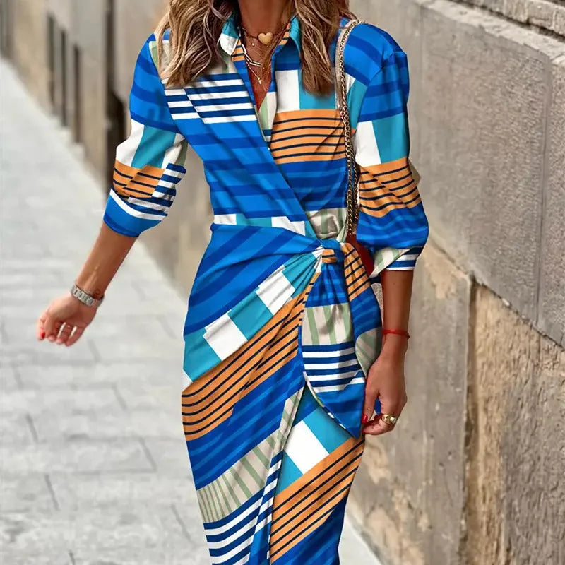 Woman wearing a colorful striped dress walking on a street.