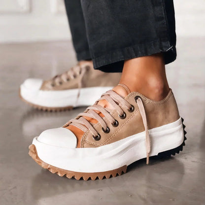 Beige sneakers with white soles worn by a person on a neutral background