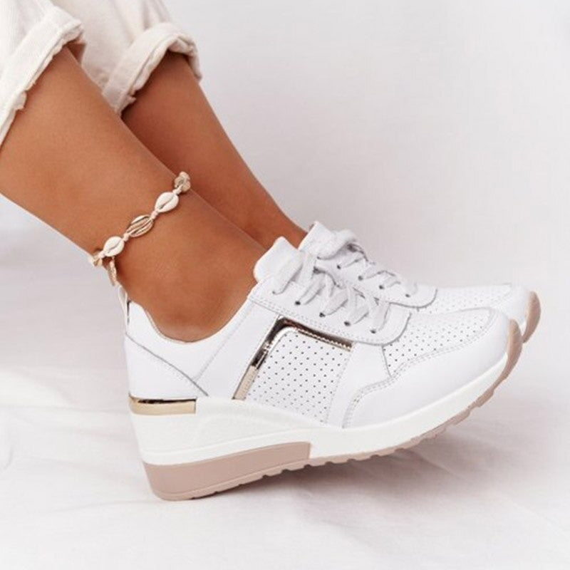 White sneaker with gold accents worn by a person on a light background