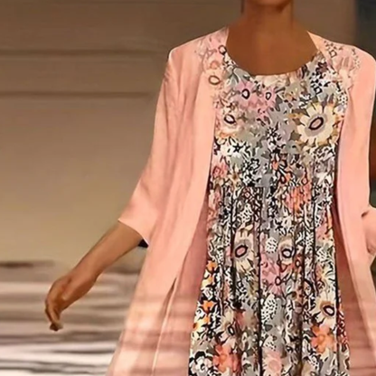Woman wearing a floral dress with a pink cardigan on a runway.