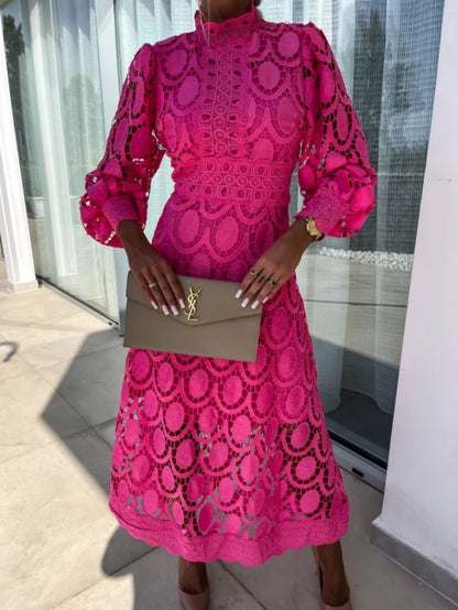 Person wearing a bright pink lace outfit holding a YSL handbag.