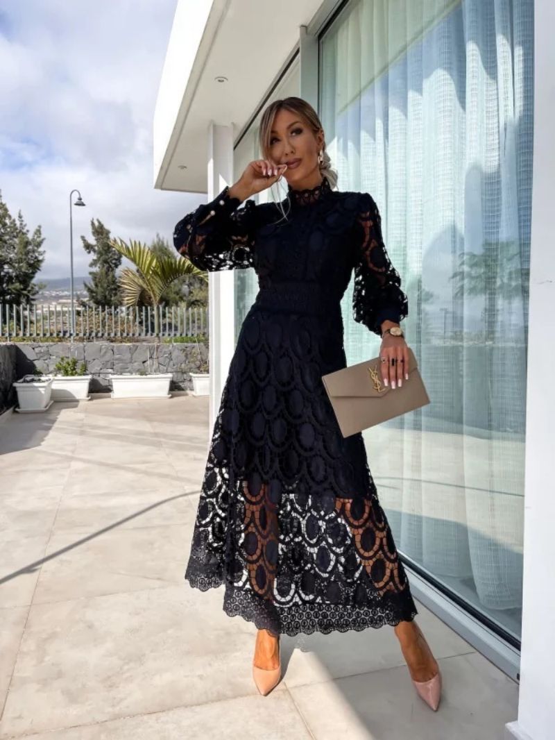 Woman in a black lace dress standing outside a modern building.