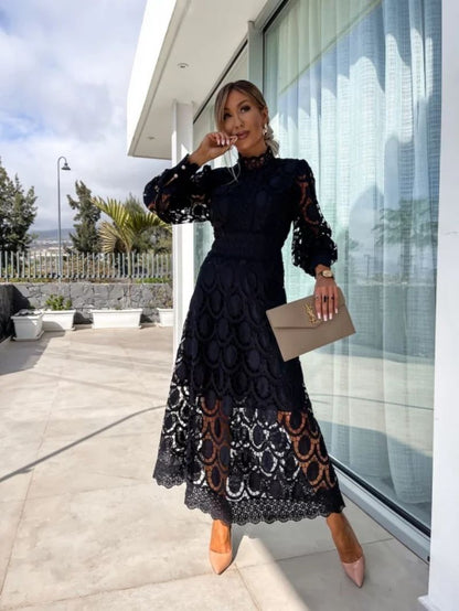 Woman in a black lace dress standing outside a modern building.