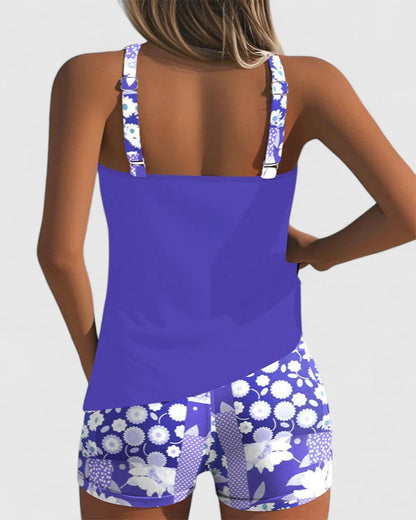 Person wearing a blue swimsuit with white floral patterns on a plain background