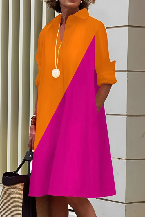 Woman wearing a colorful dress with orange and pink design, standing against a neutral background.