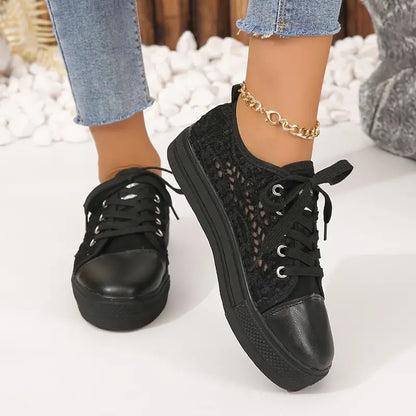 Black sneakers with a textured pattern worn with denim jeans on a light background
