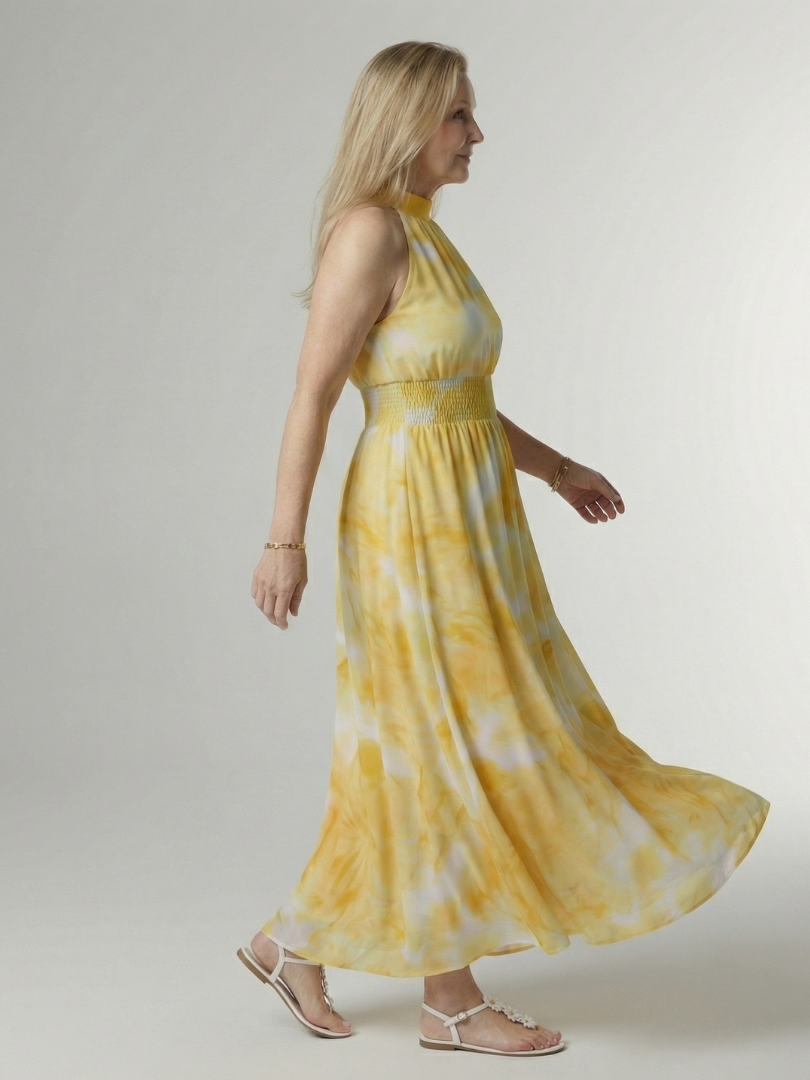 Woman wearing a yellow tie-dye dress on a plain background