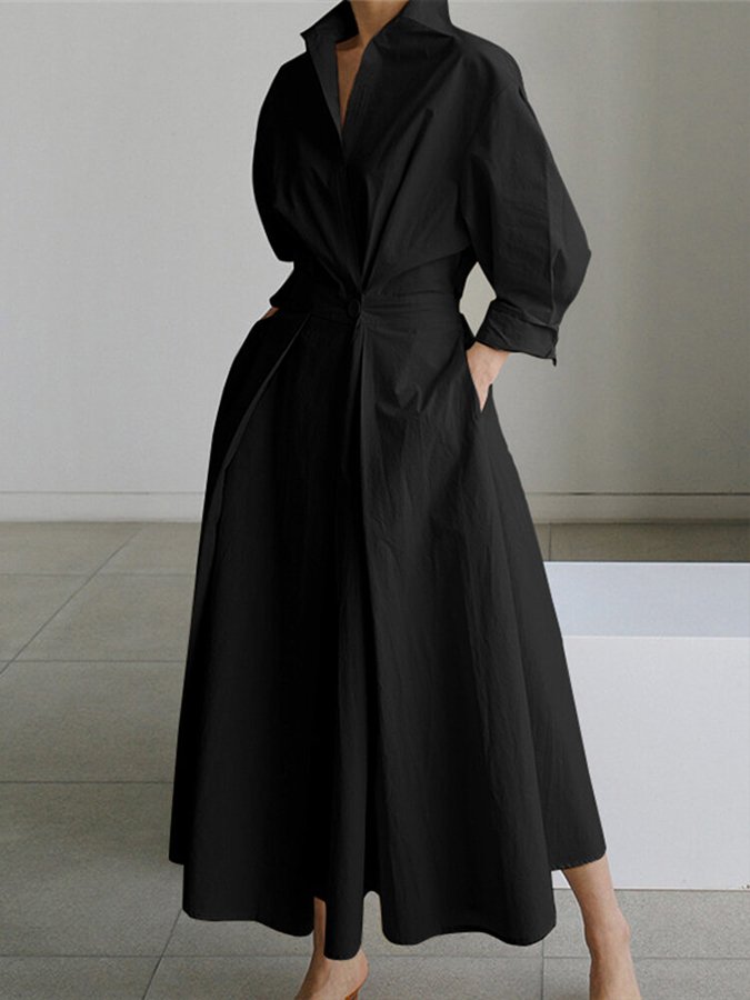 Person wearing a black dress with a tie waist in a minimalistic setting