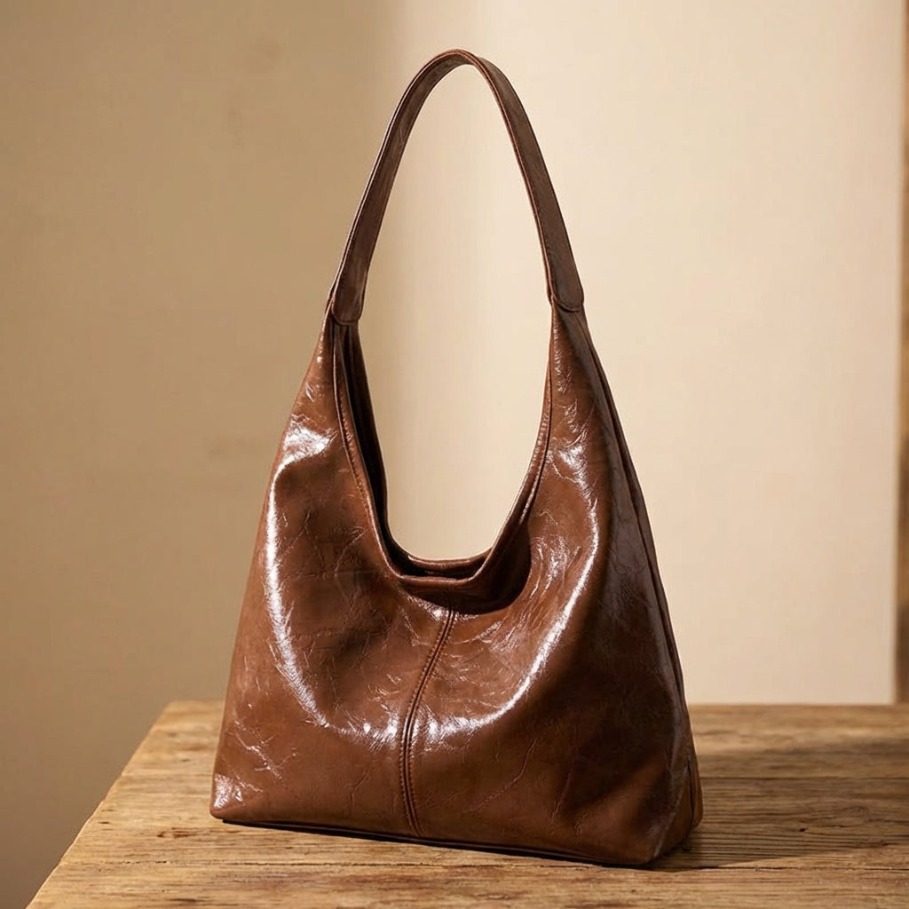 Dark brown leather vintage handbag on a wooden surface with a beige background