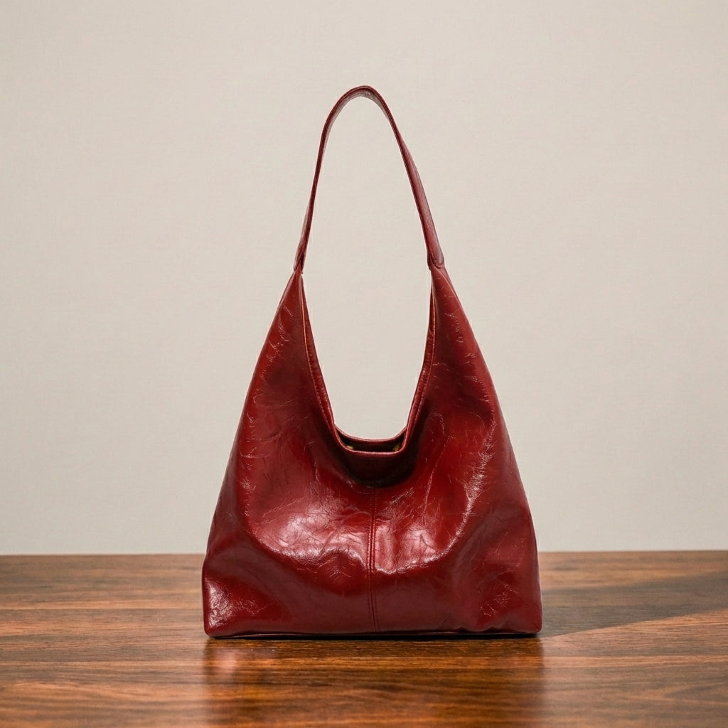 Red leather shoulder purse on a wooden surface with a beige background