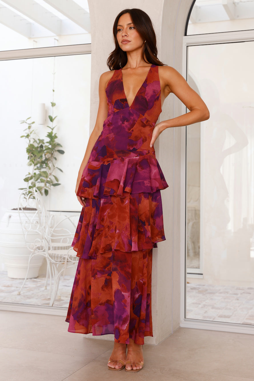 Woman wearing a colorful dress in a bright room with large windows.