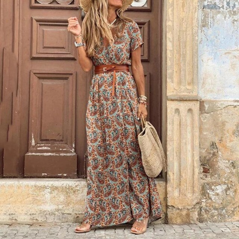 Woman in a patterned dress standing in front of a textured wall.